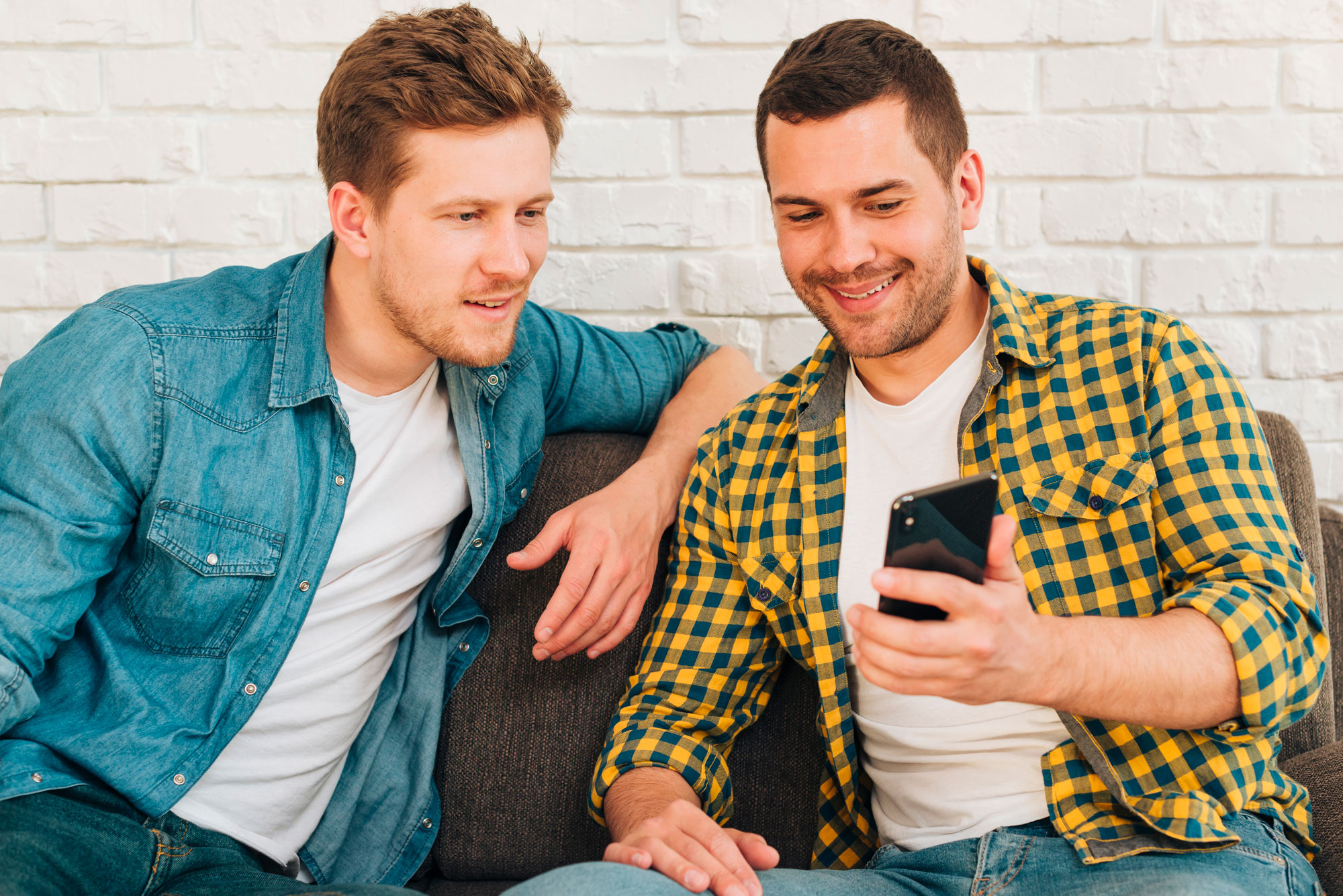 Two friends smiling looking at a cellphone